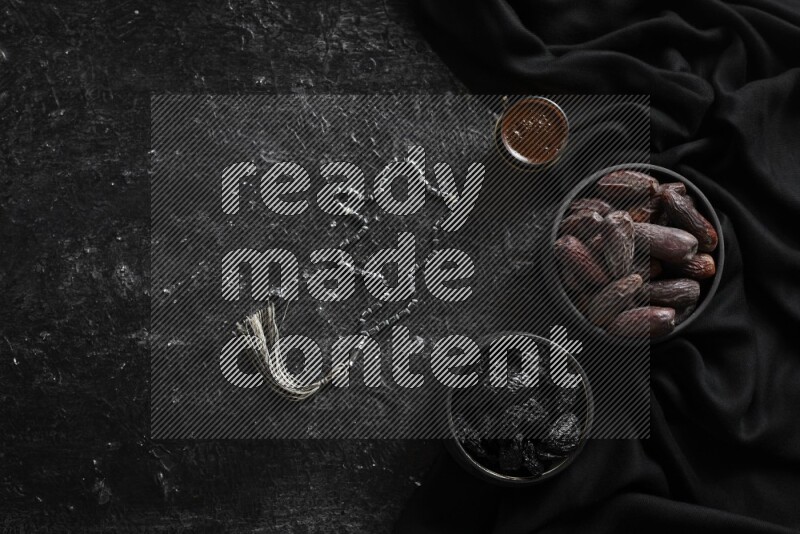 Dried fruits in pottery bowls with coffee in a dark setup