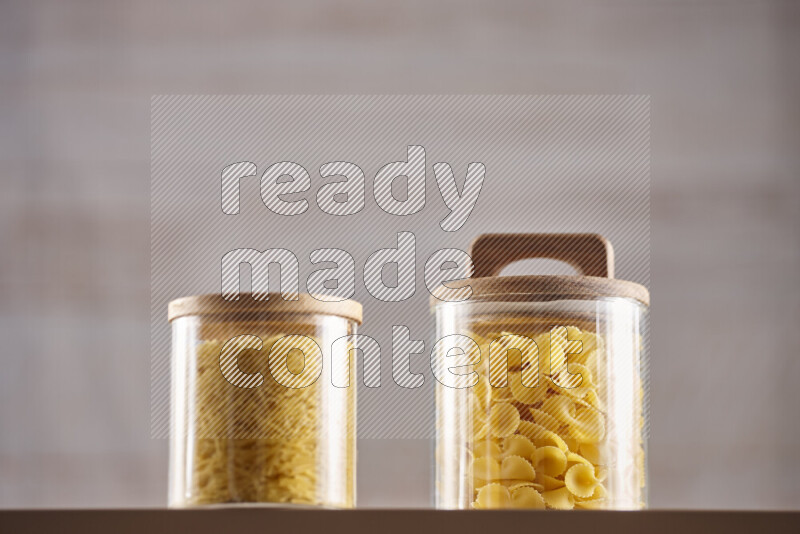Raw pasta in glass jars on beige background