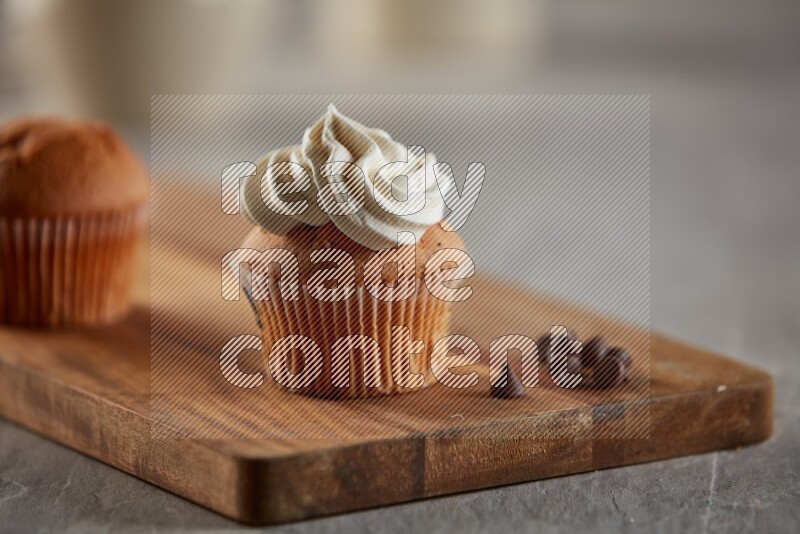 Vanilla cupcake topped with cream on a wooden board