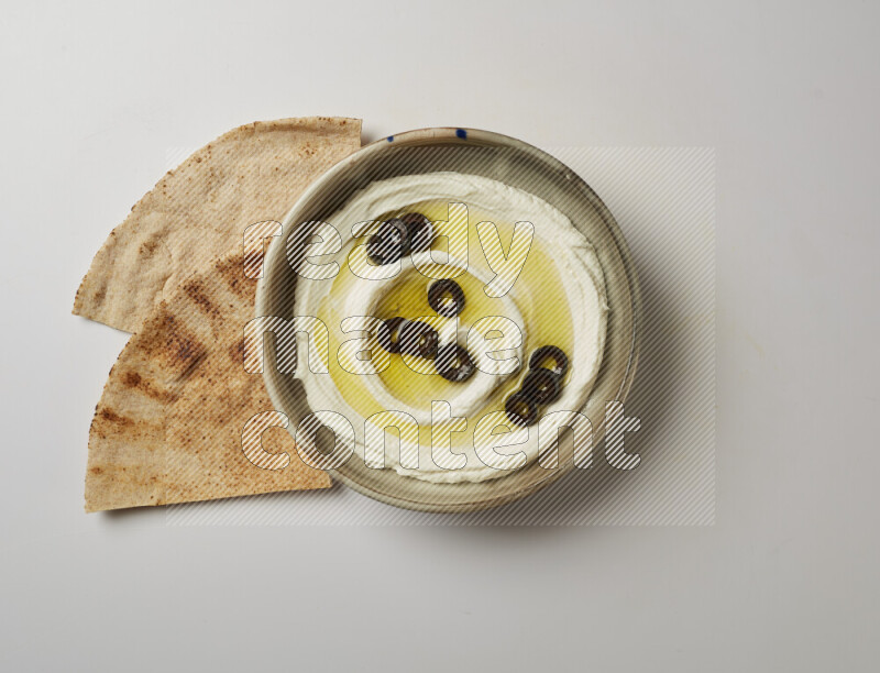 Lebnah garnished with sliced olives in a grey pottery plate on a white background