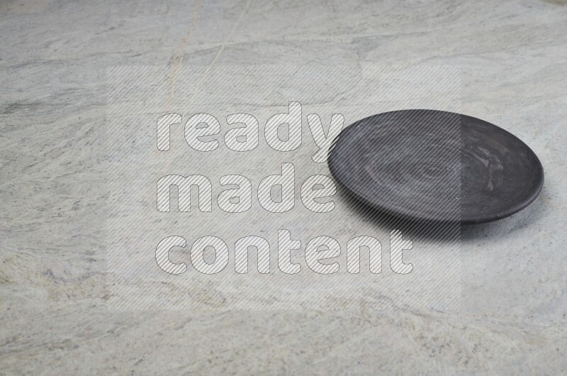 A black pottery plate on grey marble background