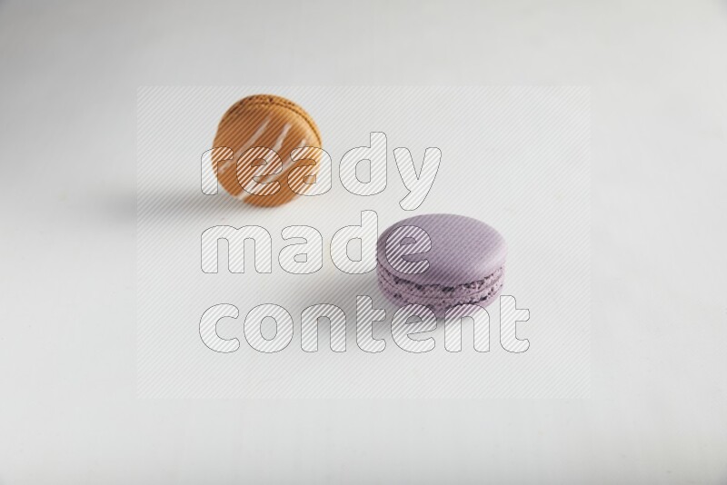 45º Shot of of two assorted Brown Irish Cream, and Purple Blueberry macarons on white background