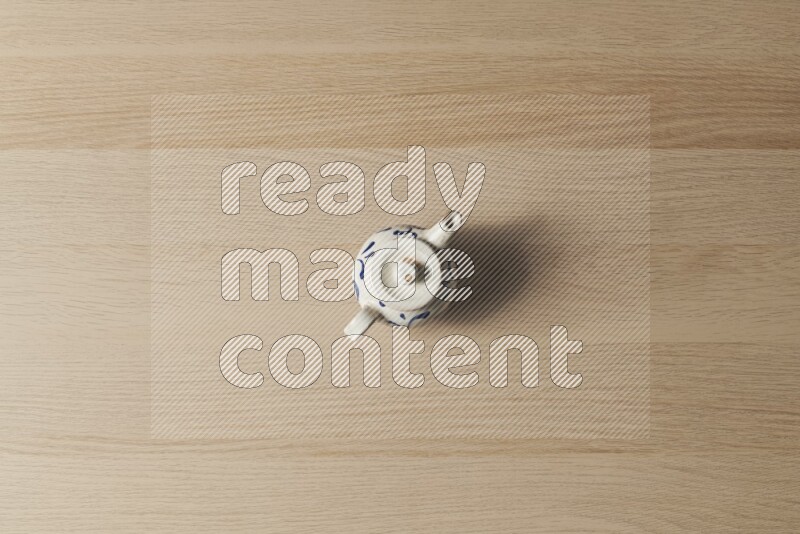 A pottery teapot on light wooden background