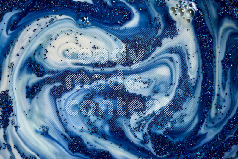 A close-up of sparkling blue glitter scattered on swirling blue and white background