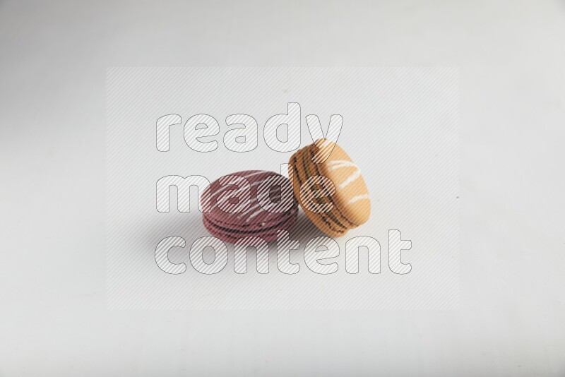 45º Shot of of two assorted Brown Irish Cream, and Red Poppy Flower macarons on white background