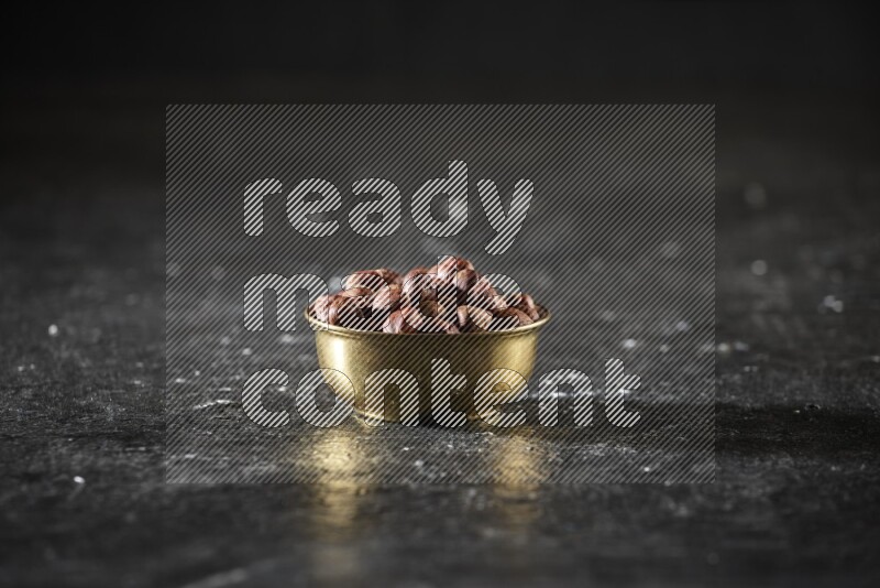 Nuts in a metal bowl in a dark setup
