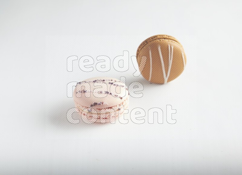 45º Shot of of two assorted Brown Irish Cream, and pink orange blossom macarons on white background