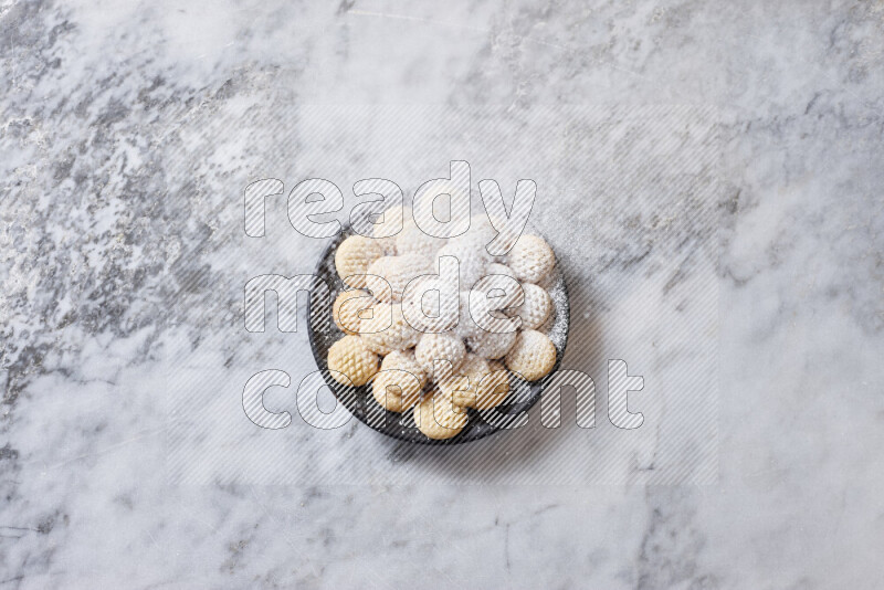 كحك في صحن فخار أسود على خلفية رخام رمادي