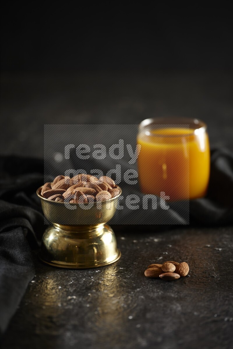 Nuts in a metal bowl with qamar eldin and a napkin in a dark setup
