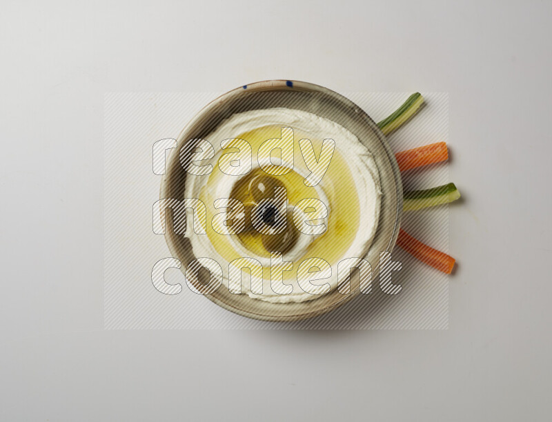 Lebnah garnished with whole olives in a grey pottery plate on a white background
