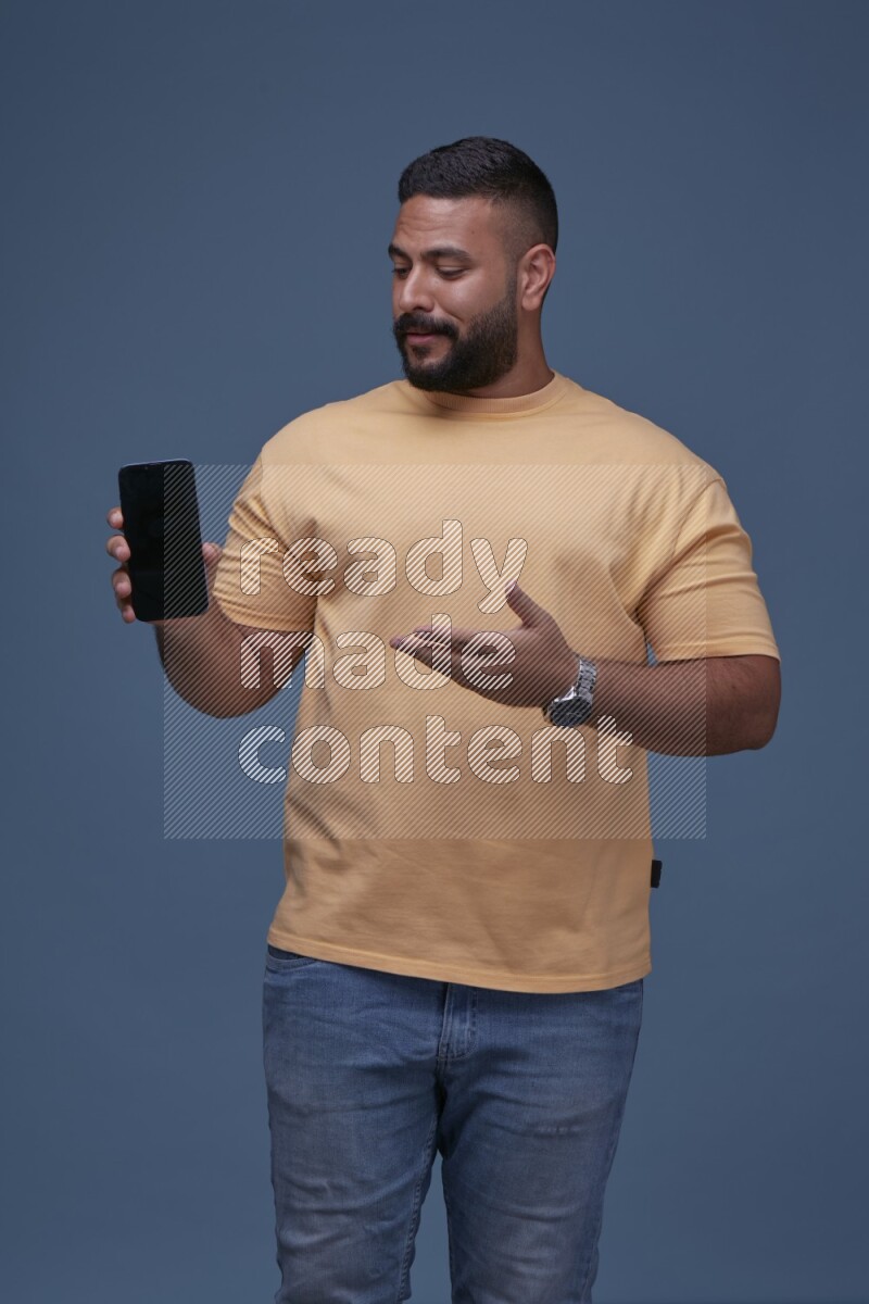 A man Showing His Smart Phone on Blue Background wearing Orange T-shirt