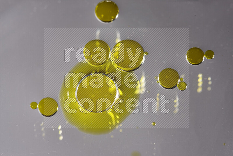 Close-ups of abstract yellow watercolor drops on oil Surface on white background