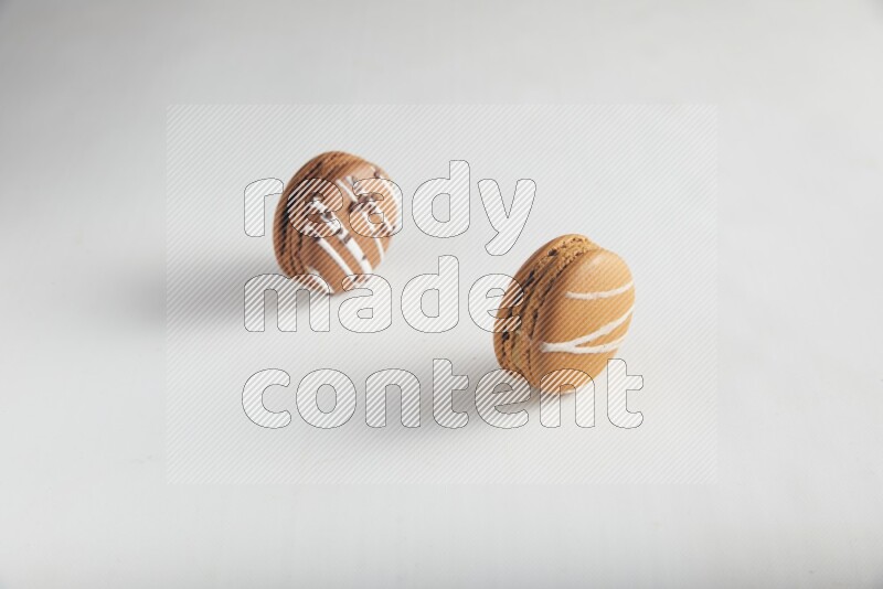 45º Shot of of two assorted Brown Irish Cream, and Brown white Chocolate Caramel macarons on white background