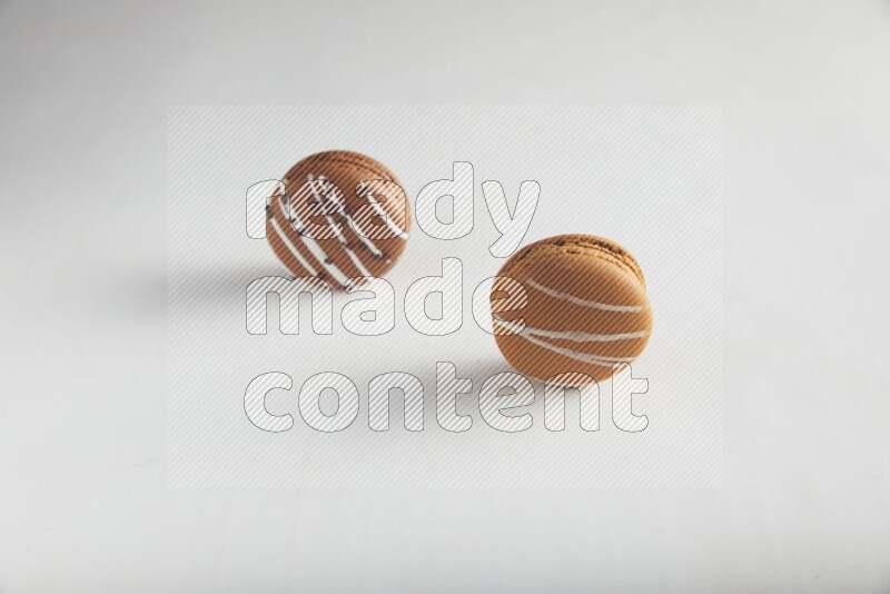 45º Shot of of two assorted Brown Irish Cream, and Brown white Chocolate Caramel macarons on white background