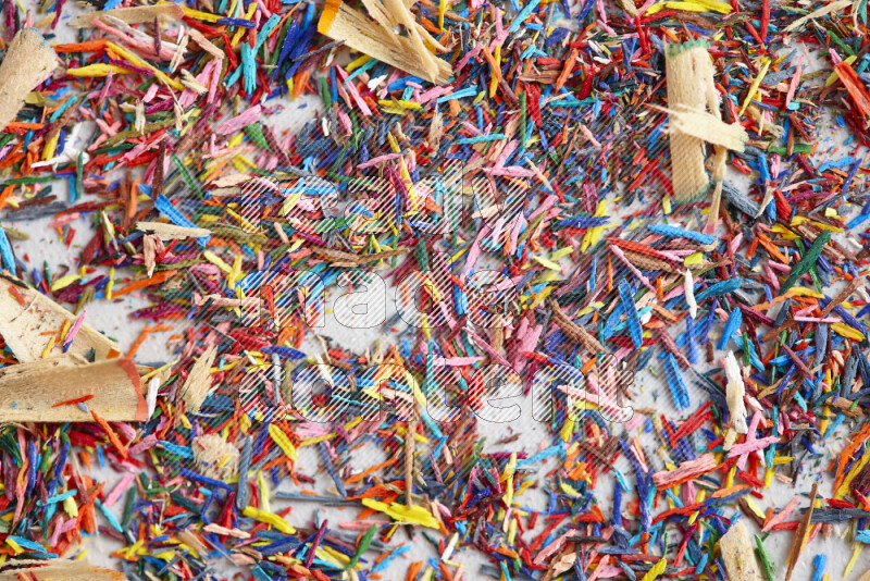 This image showcases a vibrant multicolored pencil shavings scattered on grey background