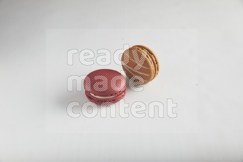 45º Shot of of two assorted Brown Irish Cream, and Red Velvet macarons on white background