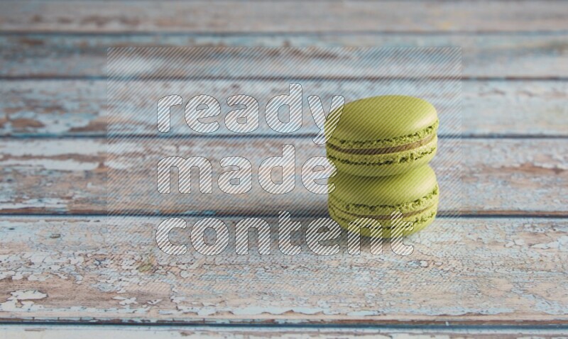 45º Shot of two Green Pistachio macarons on light blue wooden background
