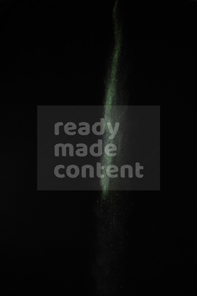 A side view of green powder explosion on black background