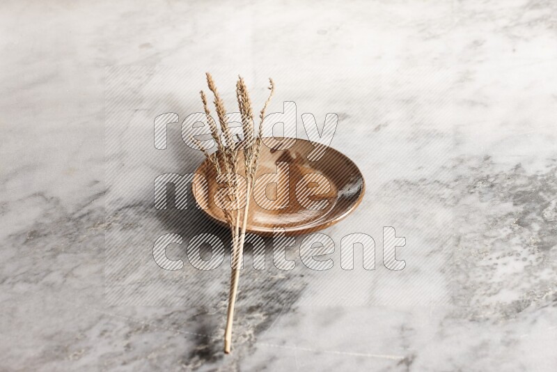 Wheat stalks on multicolored pottery plate on grey marble background