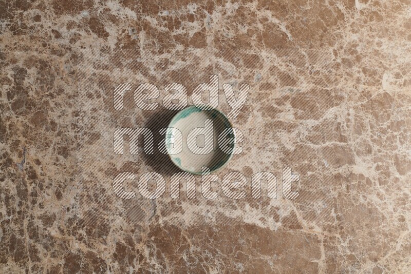 A multicolored pottery bowl on beige marble background