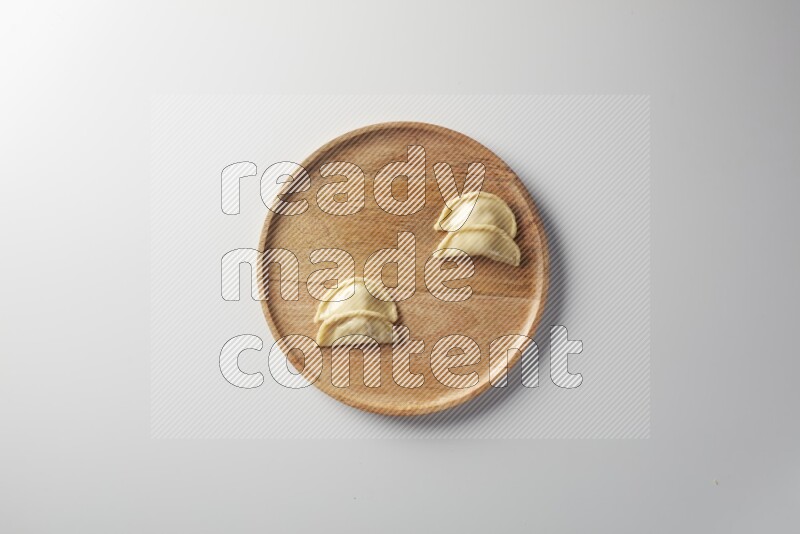 Four Sambosas on a wooden round plate on a white background