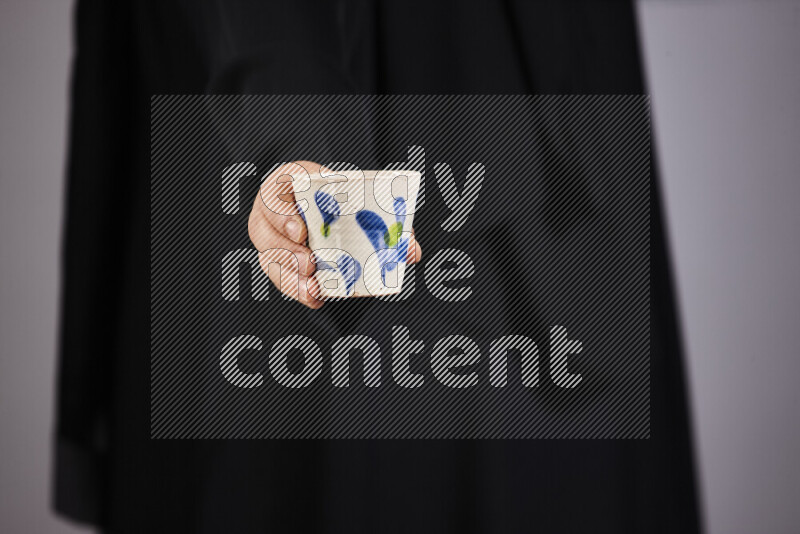 A woman in black abaya holding different pottery essentials in different positions