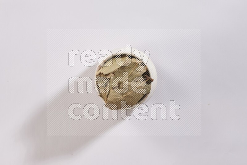 وعاء فخاري بيج ممتلئ بأوراق الغار المجففة على أرضية بيضاء