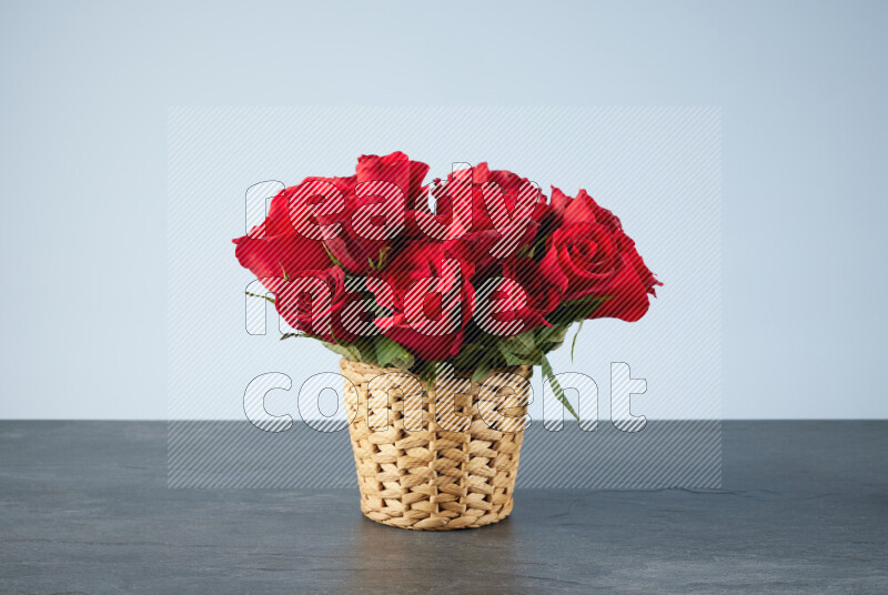 Vibrant red roses in a wicker basket on black marble background