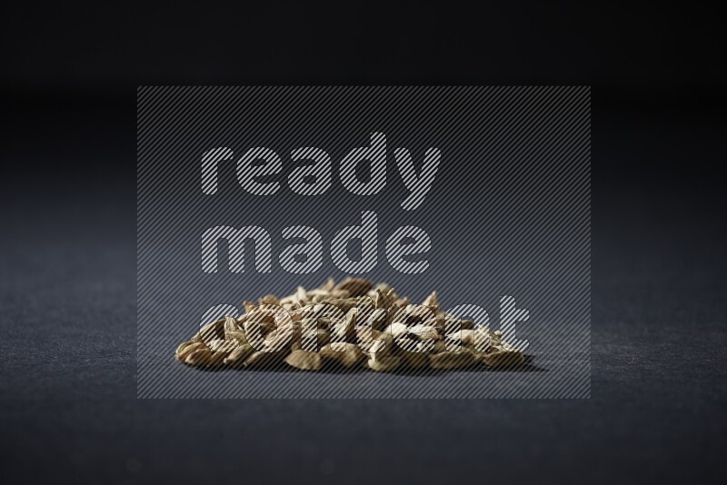 Cardamom in a triangle shape on black flooring