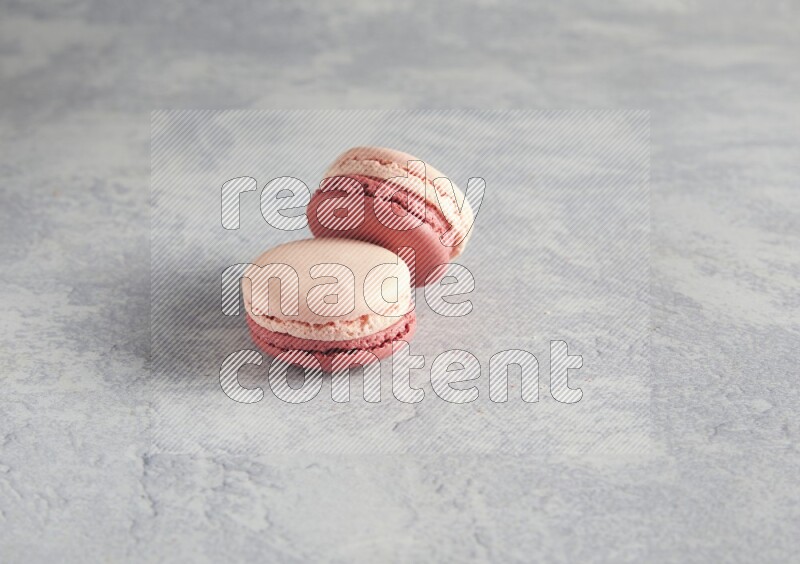 45º Shot of two Pink Litchi Raspberry macarons  on white  marble background