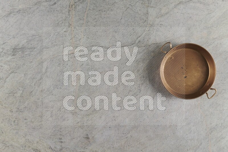 A small copper pan on grey marble background