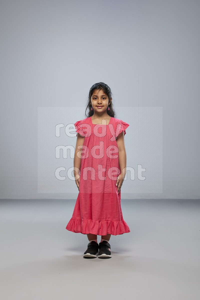 A girl standing interacting with the camera on gray background