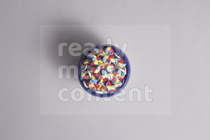 A multicolored pottery bowl full colored buttons on grey background