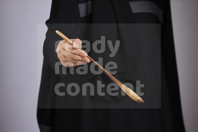 A woman in black abaya holding different wooden essentials in different positions