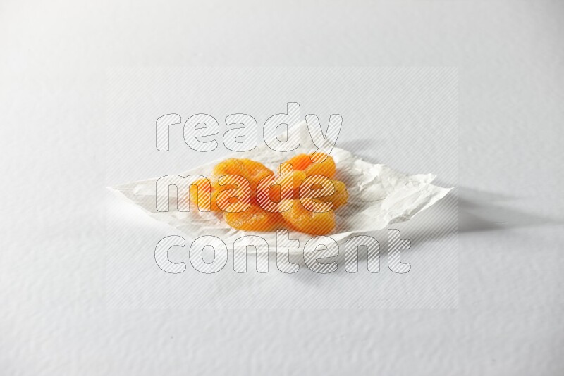 Dried apricots on a crumpled piece of paper on a white background in different angles