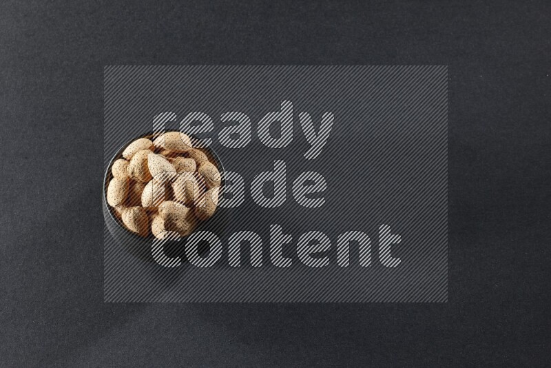 وعاء فخاري أسود ممتلئ باللوز على خلفية سوداء