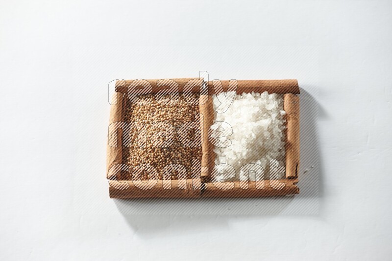 2 squares of cinnamon sticks full of mustard seeds and white salt on white flooring