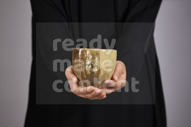 A woman in black abaya holding different pottery essentials in different positions