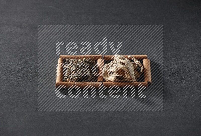 2 squares of cinnamon sticks full of dried ginger and dried basil on black flooring