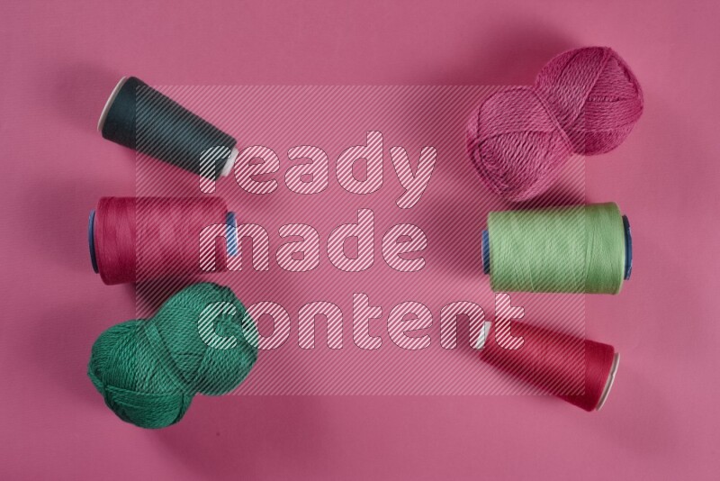 A green and pink collection of sewing and tailoring tools arranged on a pink background