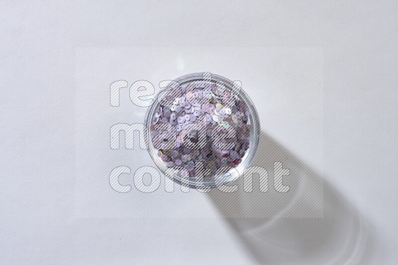 Colored flat sequins in a glass bowl on grey background