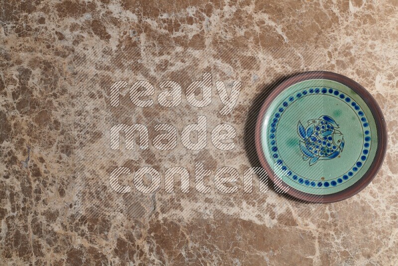A decorative pottery plate on beige marble background