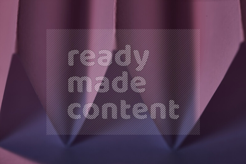 صورة مجردة مقربة تظهر طيات ورقية هندسية حادة بتدرجات اللون الارجواني