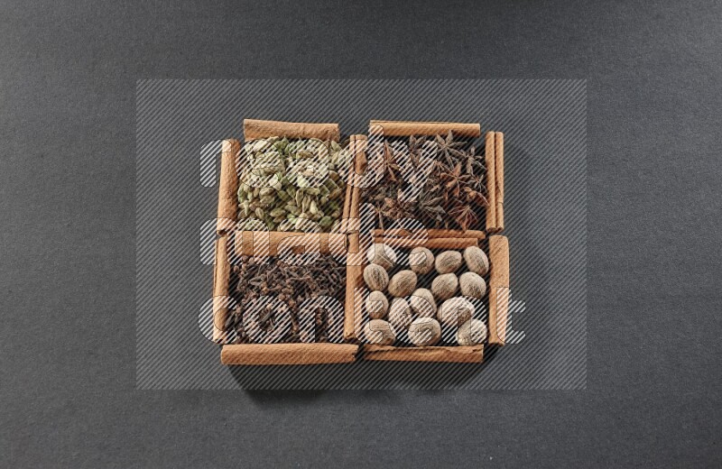 4 squares of cinnamon sticks full of cardamom, star anise, nutmegs and cloves on black flooring