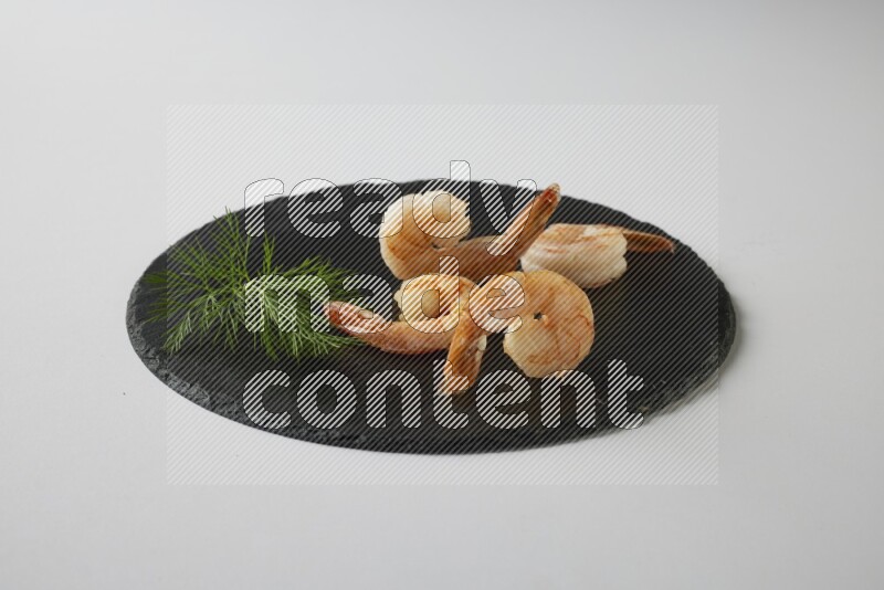 four grilled shrimp  on a black slate direct  on a white back ground
