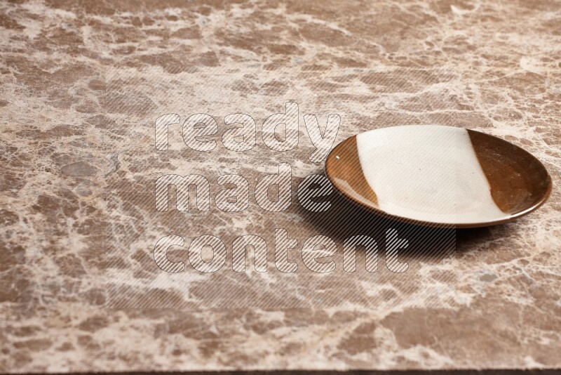 A multicolored pottery plate on beige marble background