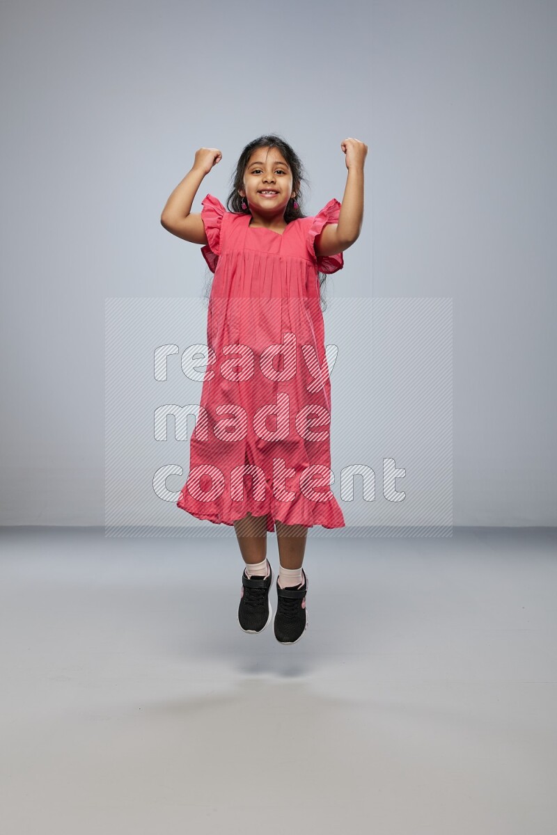 A girl standing interacting with the camera on gray background