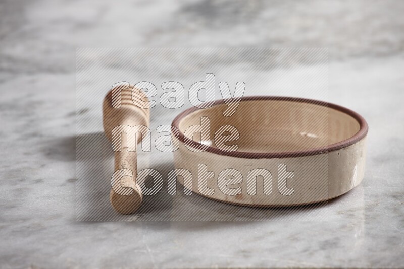 Beige pottery oven bowl with wooden honey dipper on the side on grey marble background