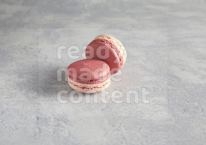 45º Shot of two Pink Litchi Raspberry macarons  on white  marble background