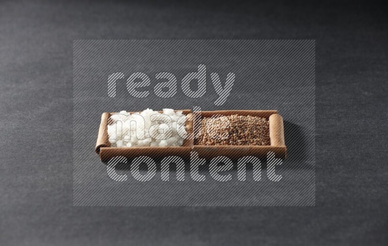 مربعان من أعواد القرفة ممتلئان بحبوب الخردل والملح الأبيض علي خلفية سوداء